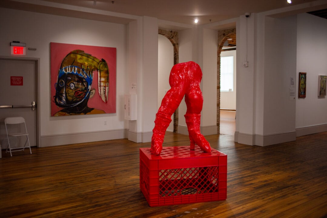 an art museum gallery with a sculpture of red legs on a red milk crate