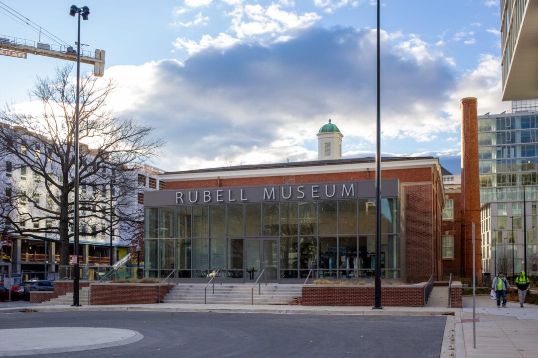 a red brick building with a glass atrium that says "rubell museum" under a cloudy blue sky