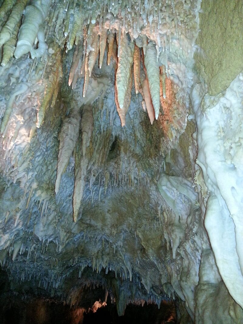 Stalactites hang from the roof of a cave