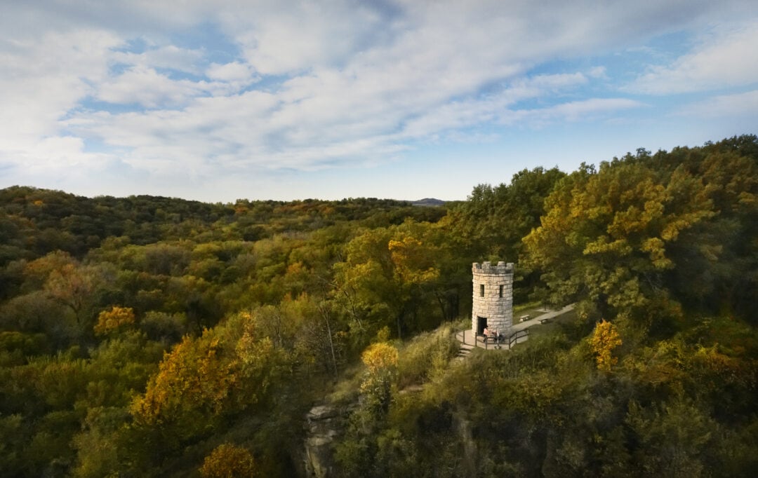 A white tower looks out at a heavily wooded landscape