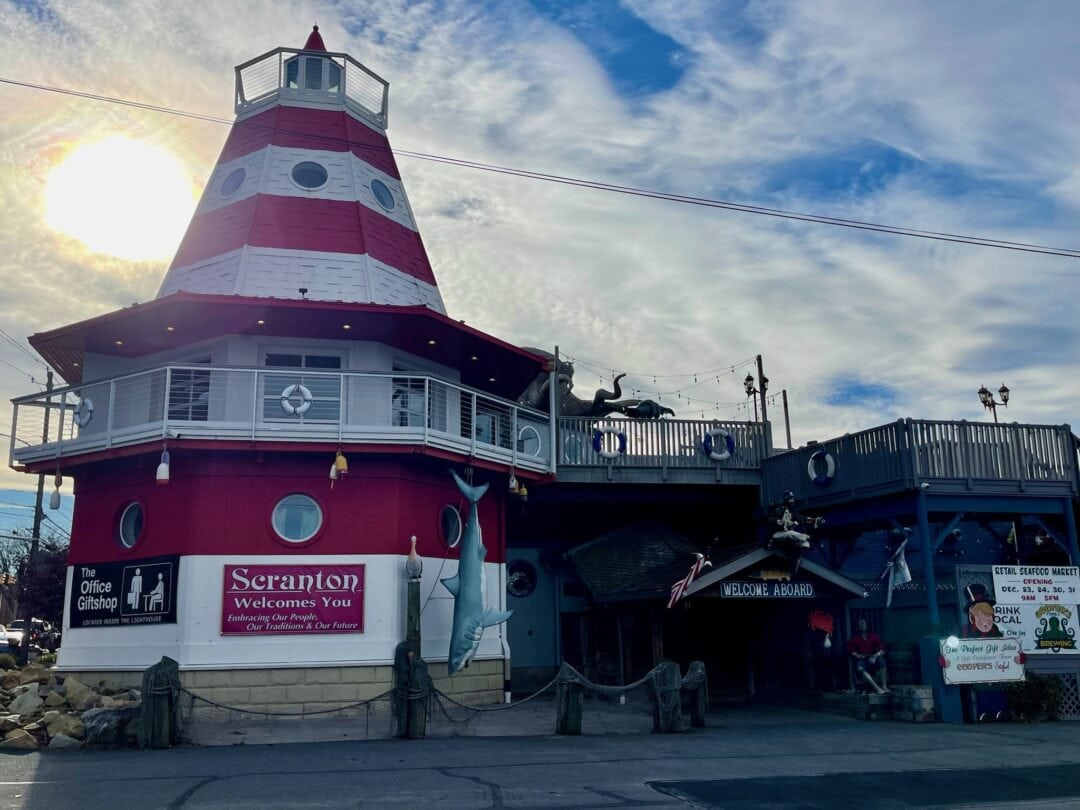 A large red and white striped lighthouse marks the entrance of a restaurant.