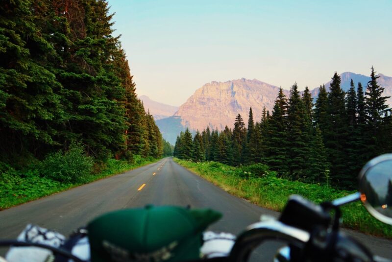 The view of colorful mountains and empty road as viewed over motorcycle handlebars