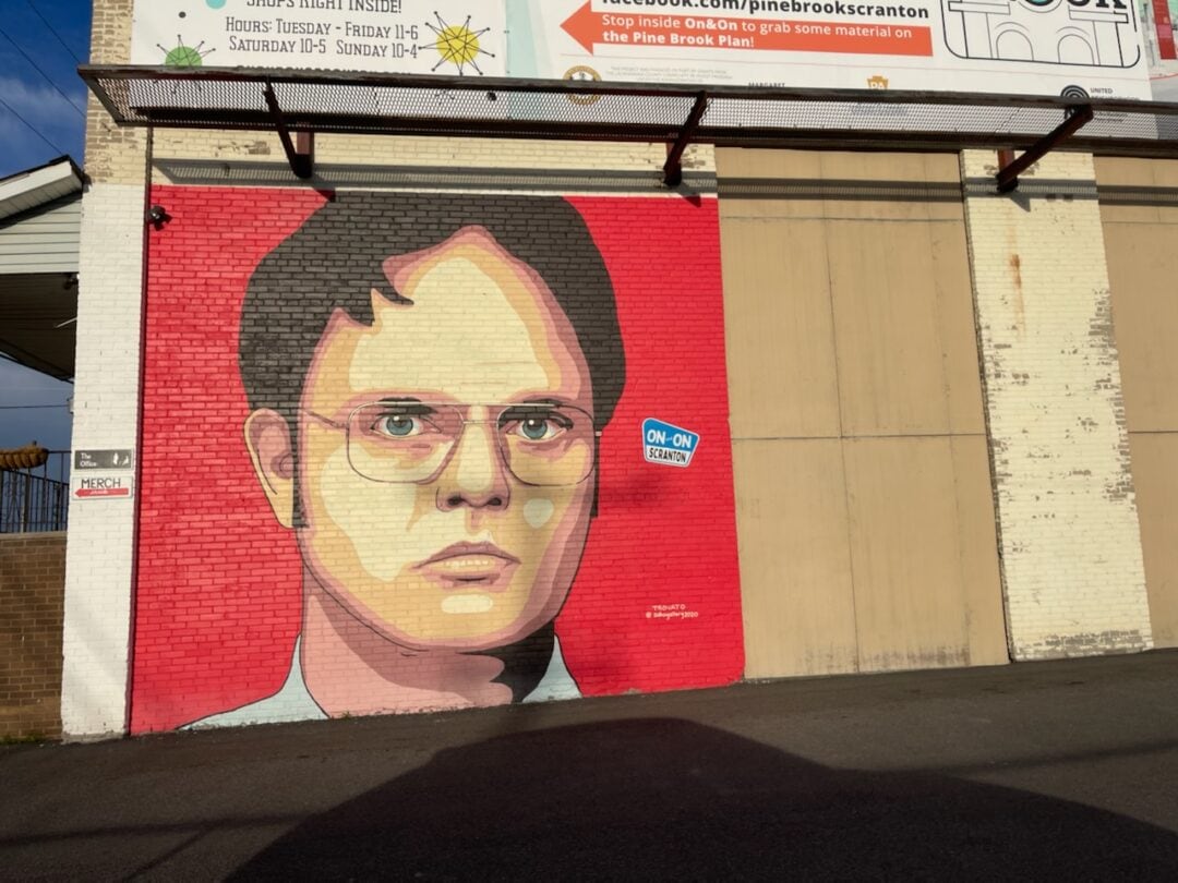 The side of a building is covered from top to bottom with a larger-than-life mural of Dwight Schrute's face.