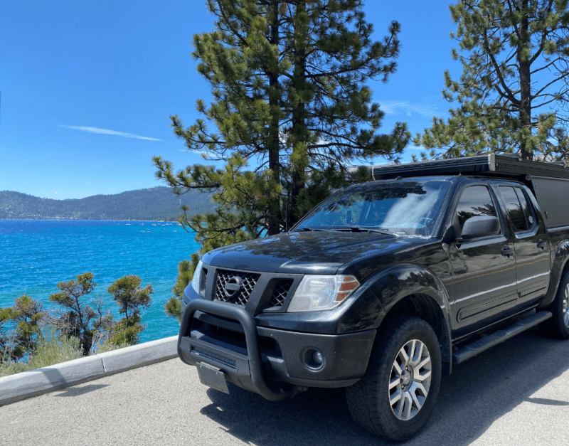 A black truck sits on the edge of the stunningly blue Lake Tahoe.