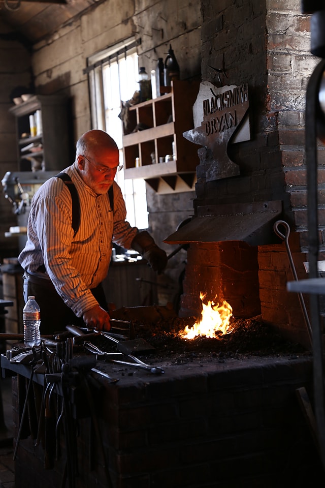A blacksmith works over an open fire.
