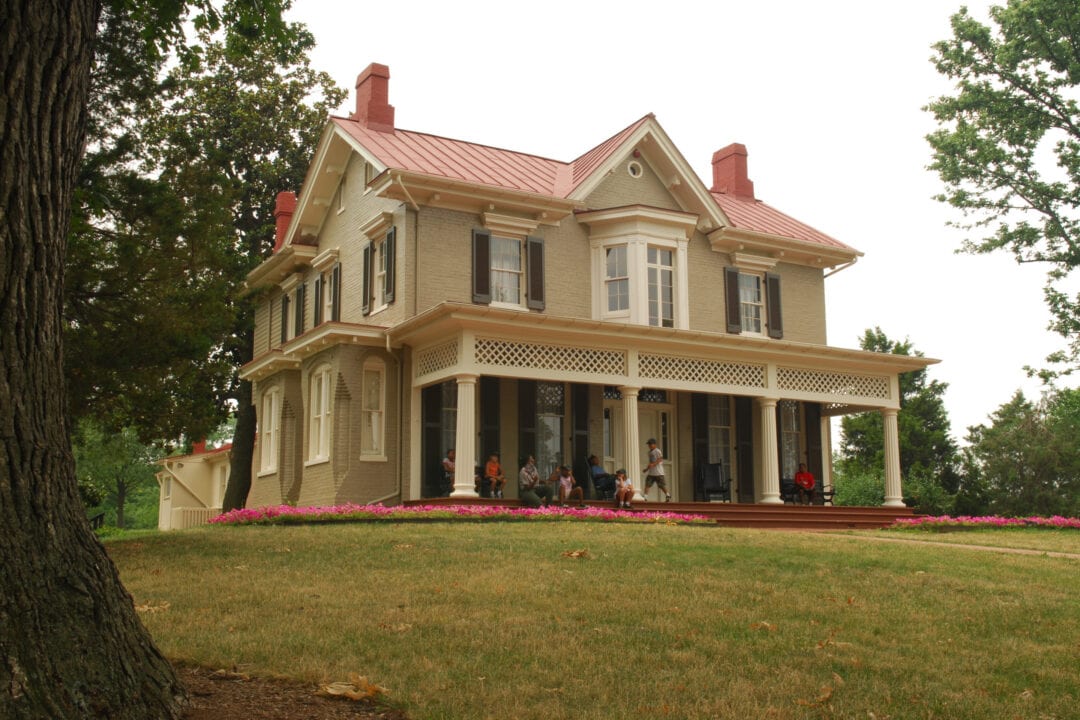 A stately, historic house sits in the middle of a green field.