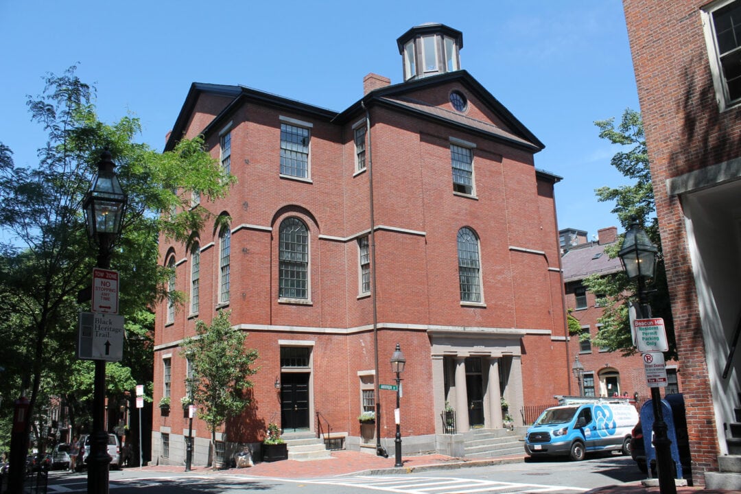 A van is parked in front of a three-story red brick building.