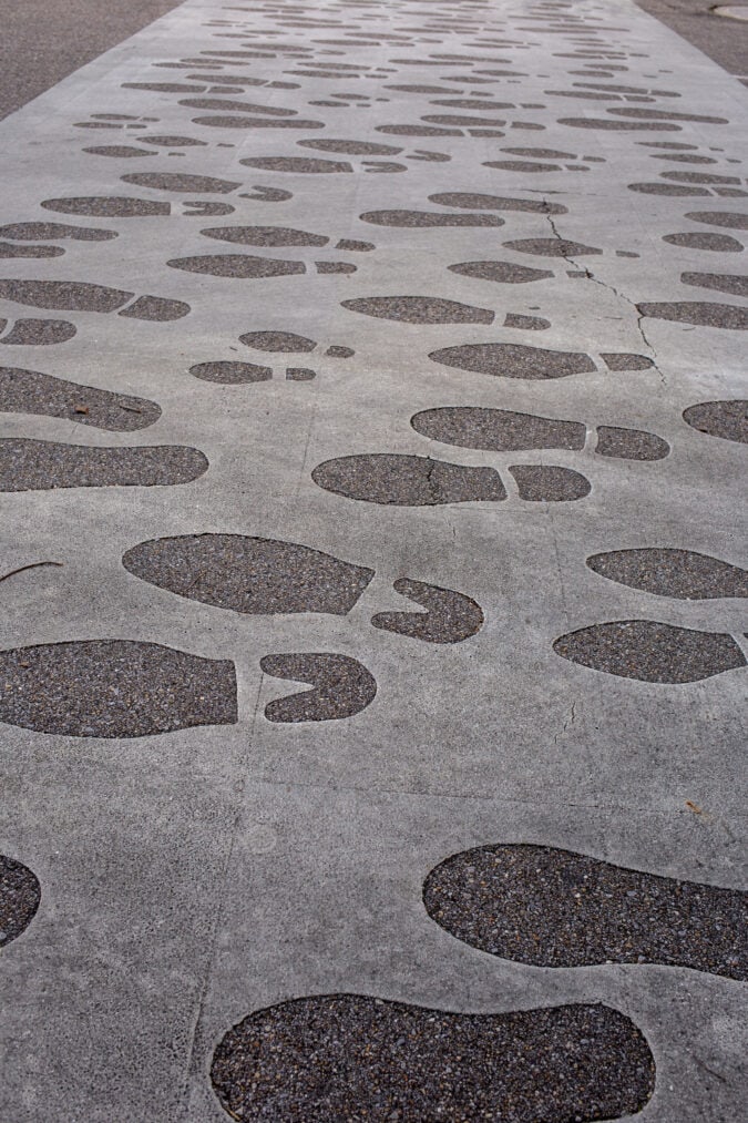 Human footprints fill a paved walkway.