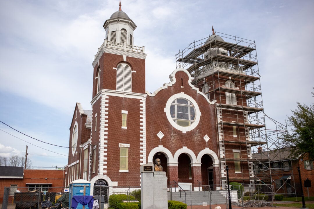 a red brick and white church with two towers, one of which is wrapped in scaffolding