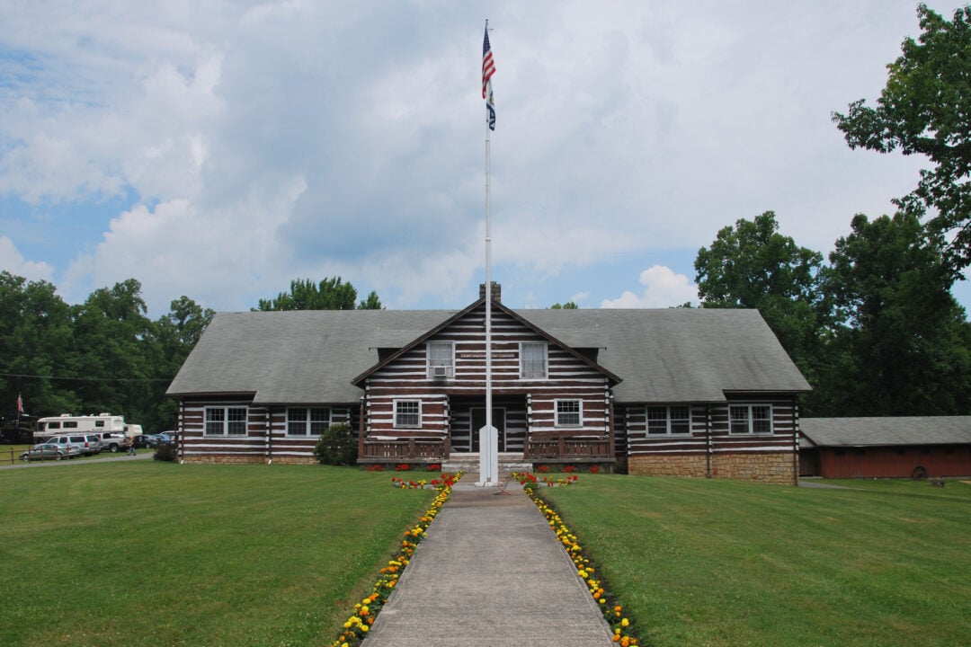 An American Flag stands in front of a rustic brown building