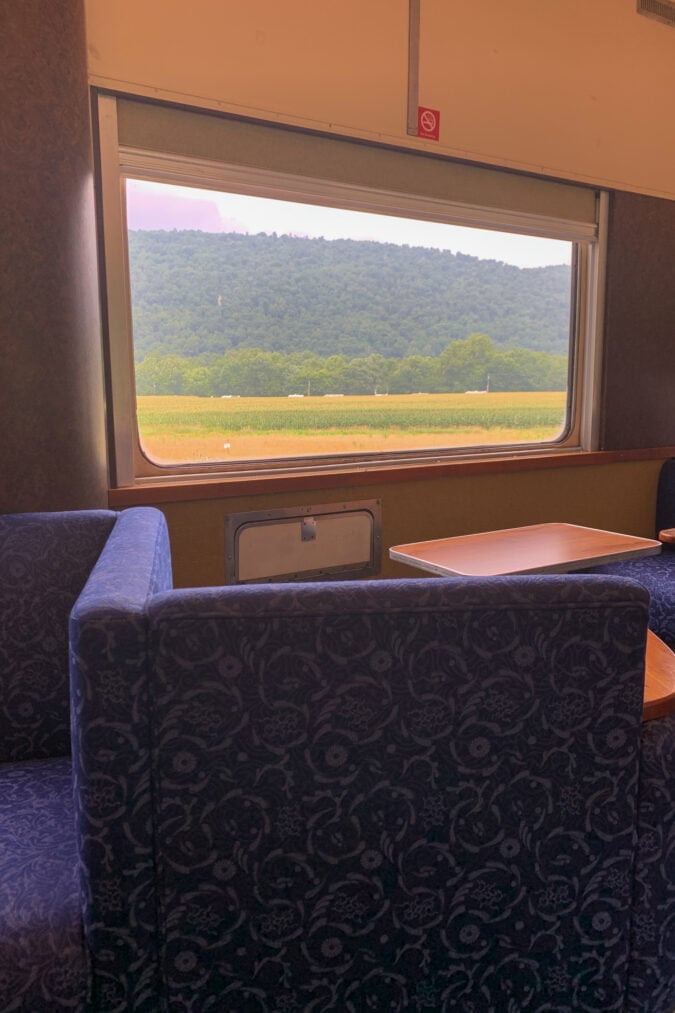 Plush seating on a train faces out the car's windows to view the scenery outside
