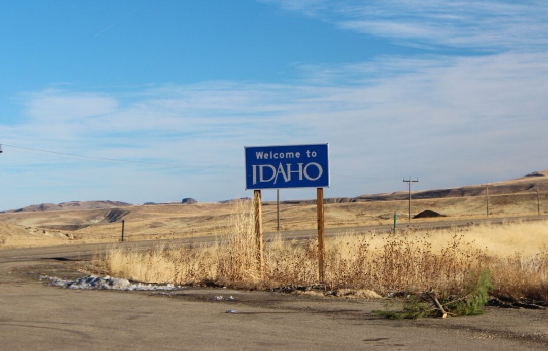 A sign along a desolate stretch of road welcomes  visitors to Idaho.