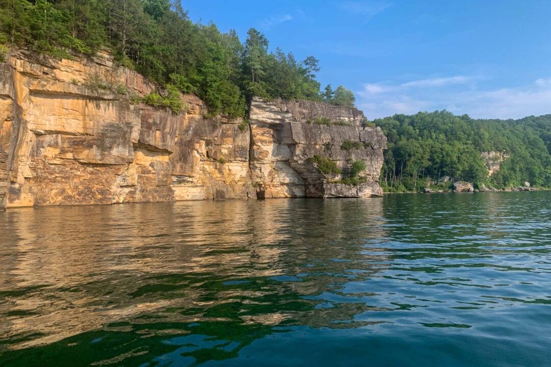 Rocky outcroppings in a lake are topped with vibrant green foliage