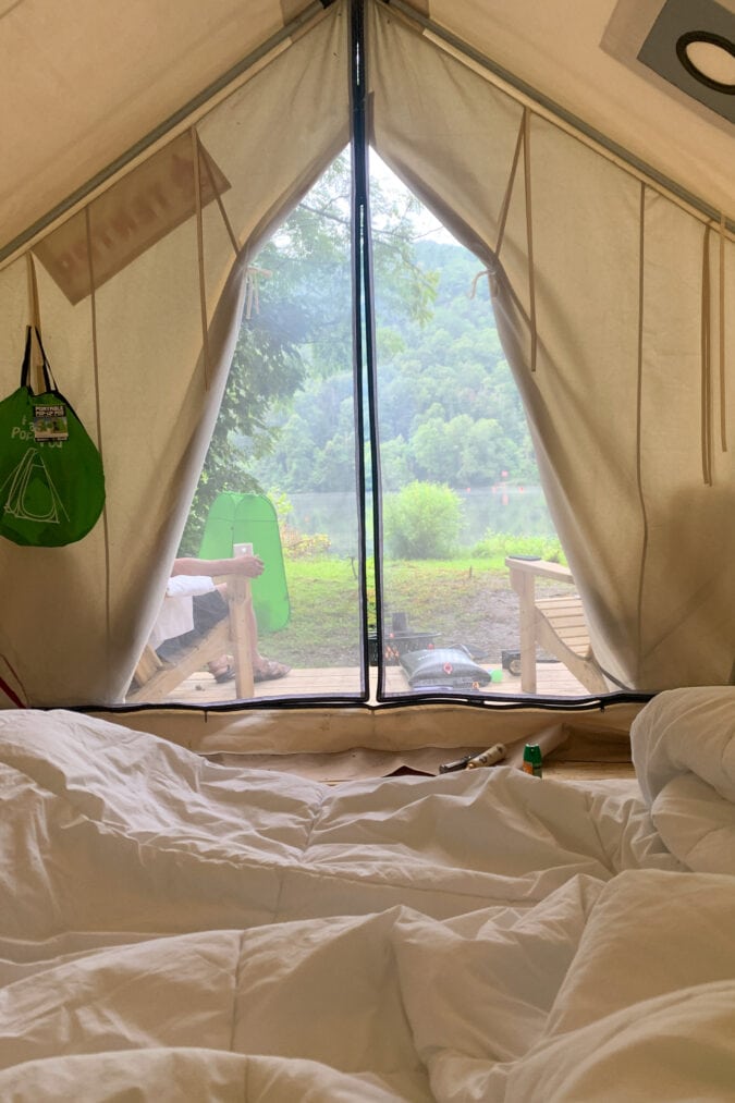 A view from inside a tent shows a screened opening with lush greenery outside