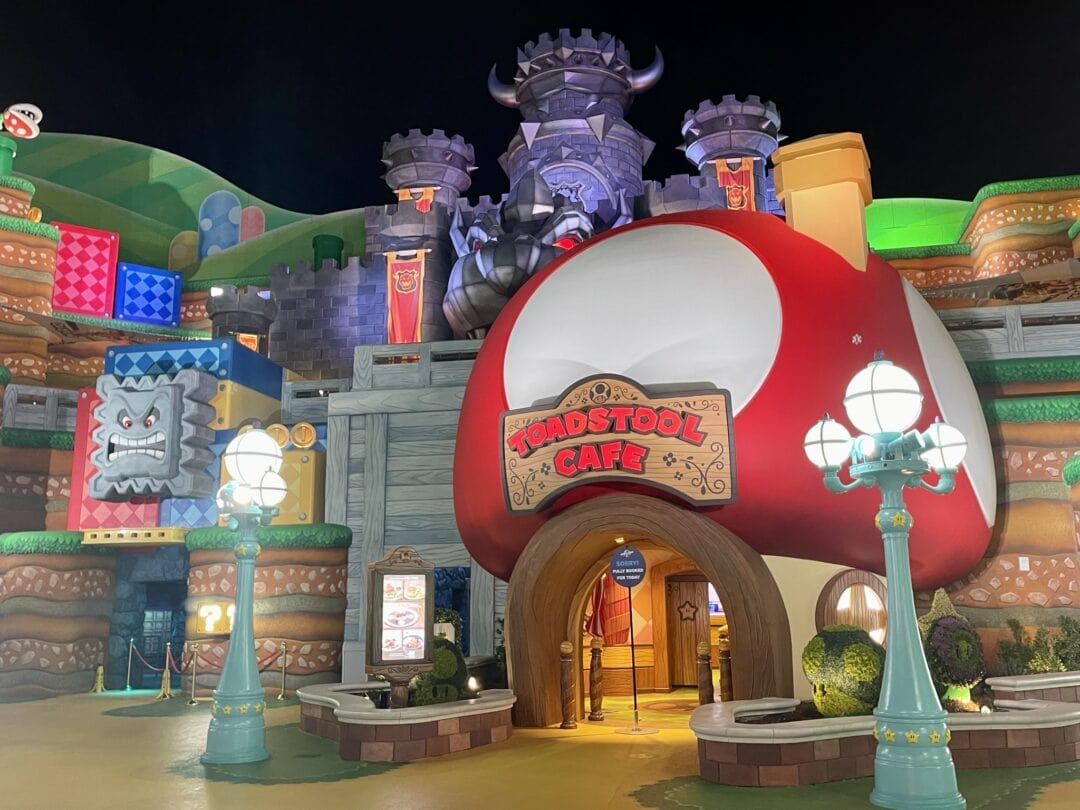 A giant toadstool-shaped eatery sits amid other larger-than-life decor elements in Super Nintendo World