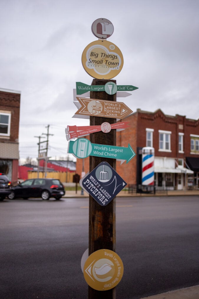 a wooden pole with directional signage along a small town main street