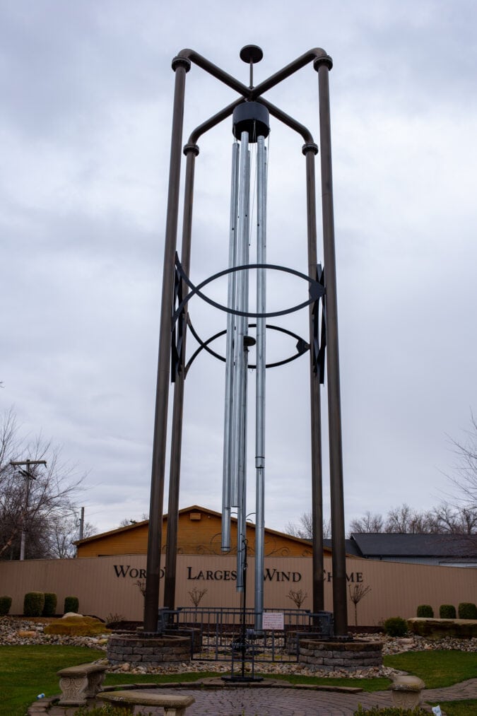 a very large metal wind chime outside against a cloudy gray sky