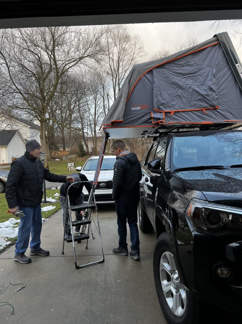 Three men standing in a driveway by a rooftop tent on a 4Runner