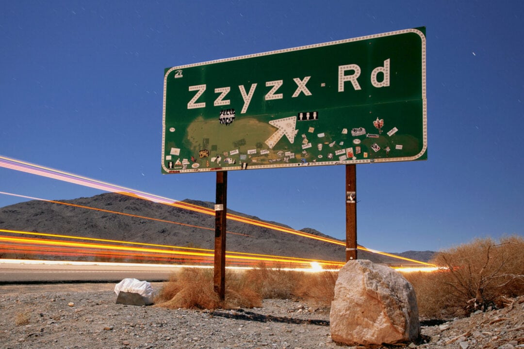 a green road sign for Zzyzx Road 