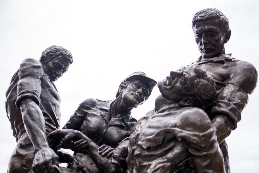 a bronze sculpture of a nurse helping three wounded men