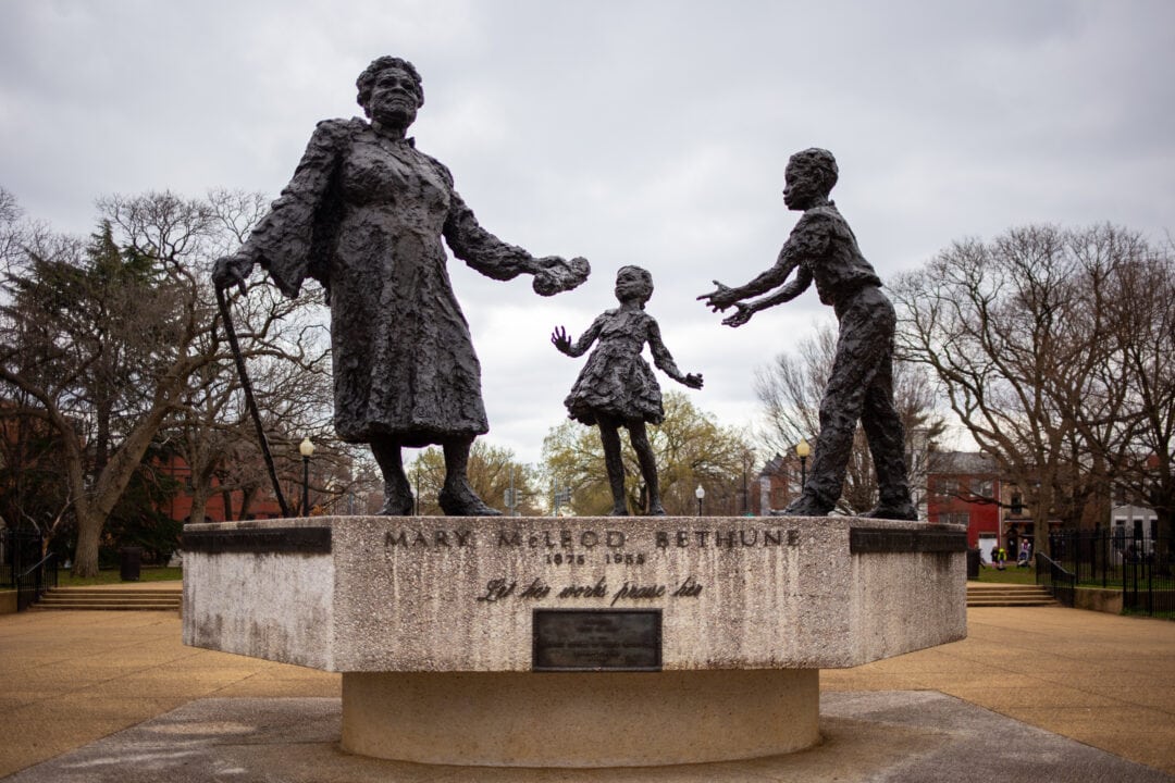 a bronze and stone statue featuring an older woman with a cane and two children dedicated to mary mcleod bethune