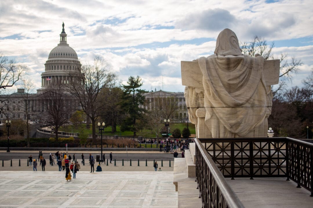 the back of a stone statue overlooking the us supreme court plaza with the capitol dome in the background