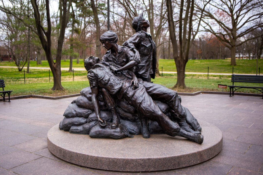 a bronze statue featuring two women nurses helping a fallen soldier