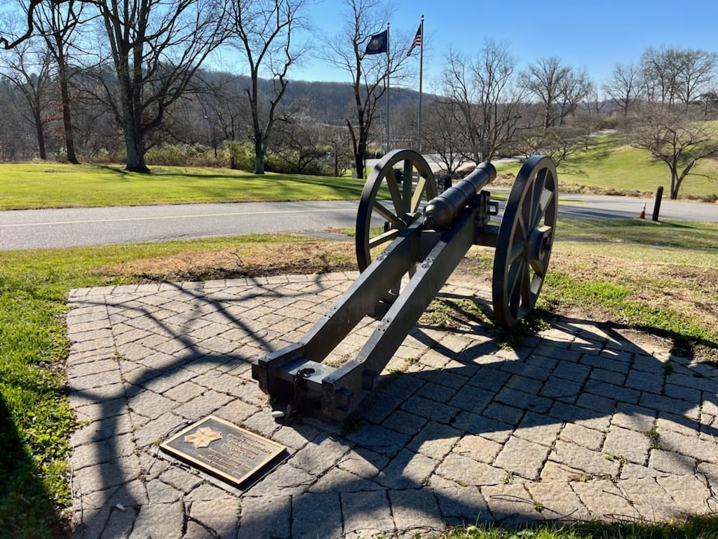 A canon sits on a hilltop overlooking a former battleground