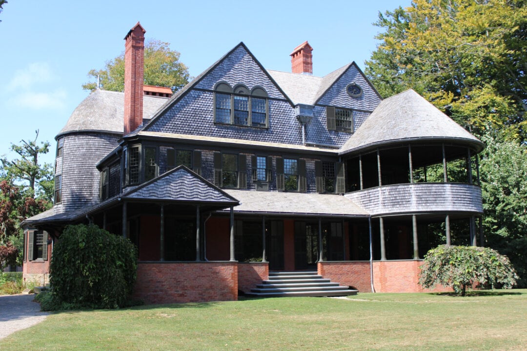 a shingle style home with a large porch and several gables 