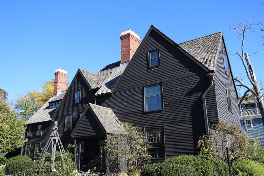 a black house with seven gables against a blue sky