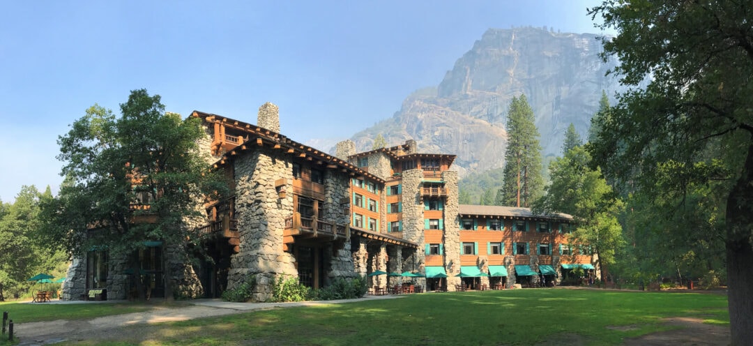 Rustic national park lodge with towering rock feature behind it