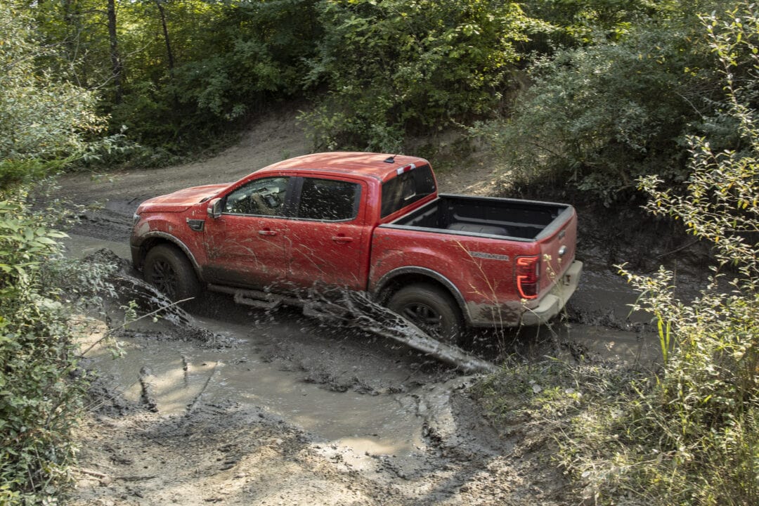 A red Ford Ranger Lariat crosses a rugged landscape