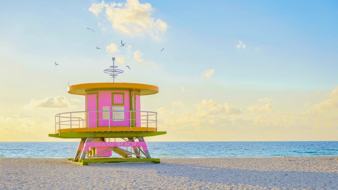 A bright pink and yellow lifeguard stand welcomes visitors to Miami Beach