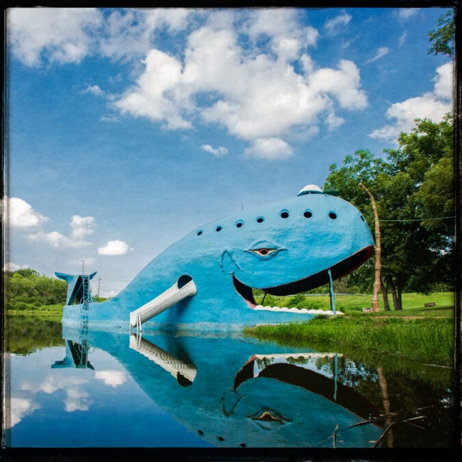 the blue whale of catoosa, a large blue whale in a swimming hole under blue skies