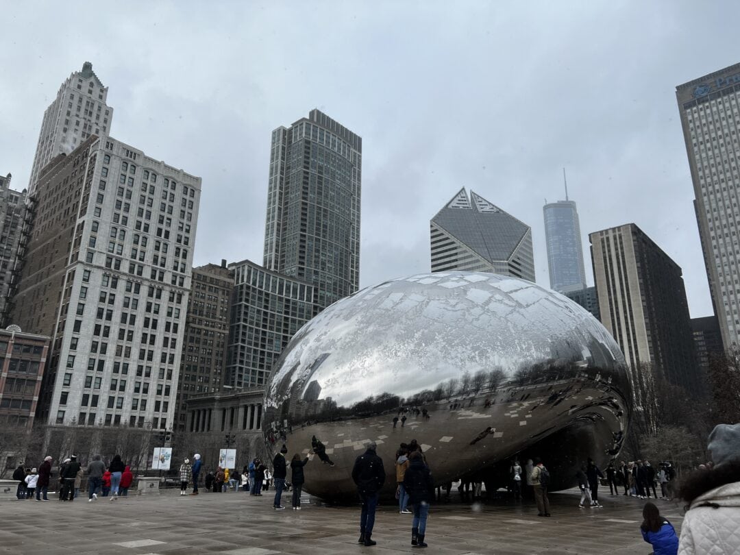 People gathered around the metallic bean-shaped sculpture in Millennium Park, downtown Chicago