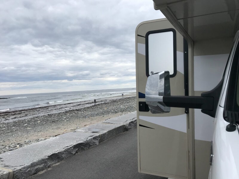 The door of an RV stands open to reveal ocean views