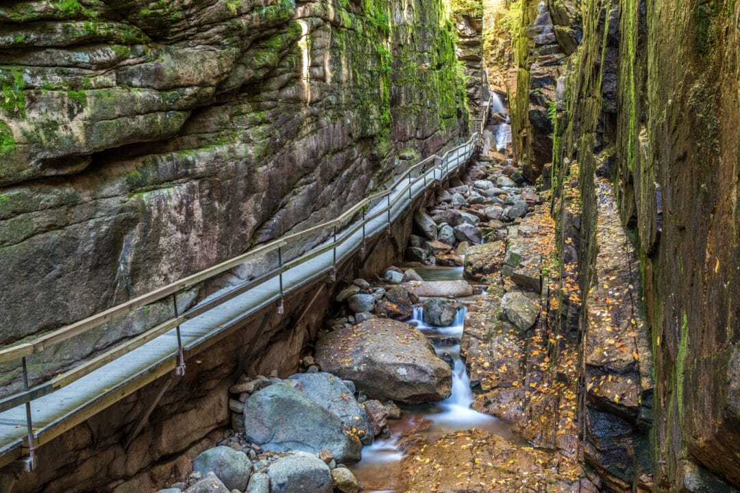 a walkway through a stone gorge above a rocky stream