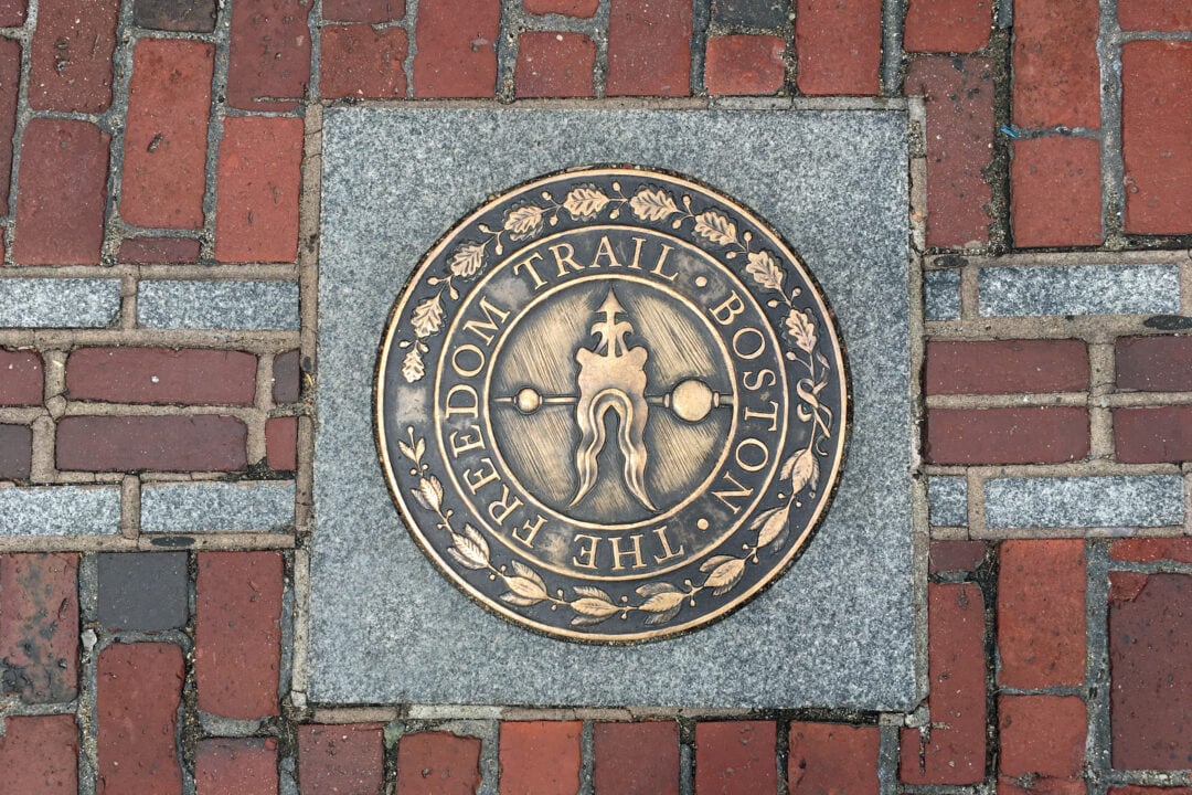 a brass marker in the brick sidewalk for the boston freedom trail