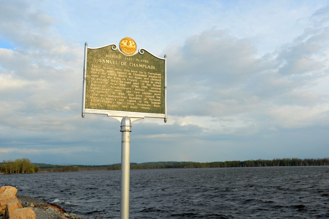 a historical marker for lake champlain stands near a lake