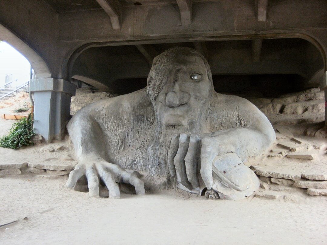 Large troll sculpture under a bridge