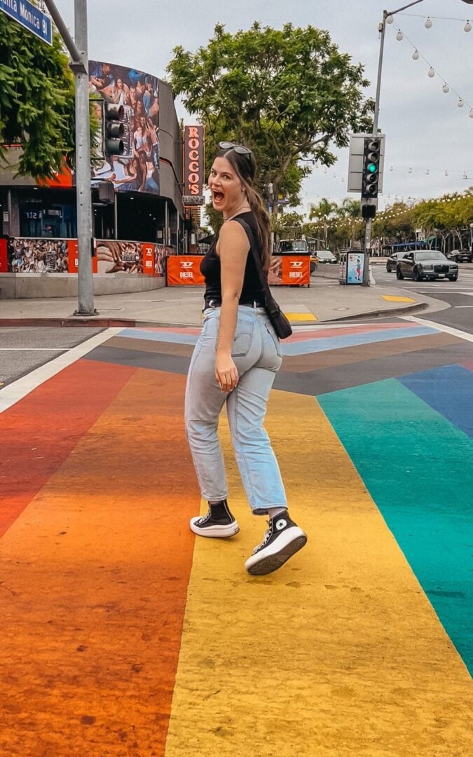 Courtney Vondran crosses a rainbow crosswalk in a city