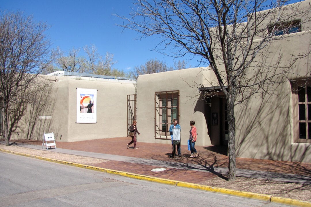 a gray adobe-style building with three people outside
