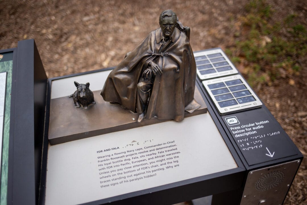 an informative plaque at the FDR memorial with a miniature version of FDR and his dog