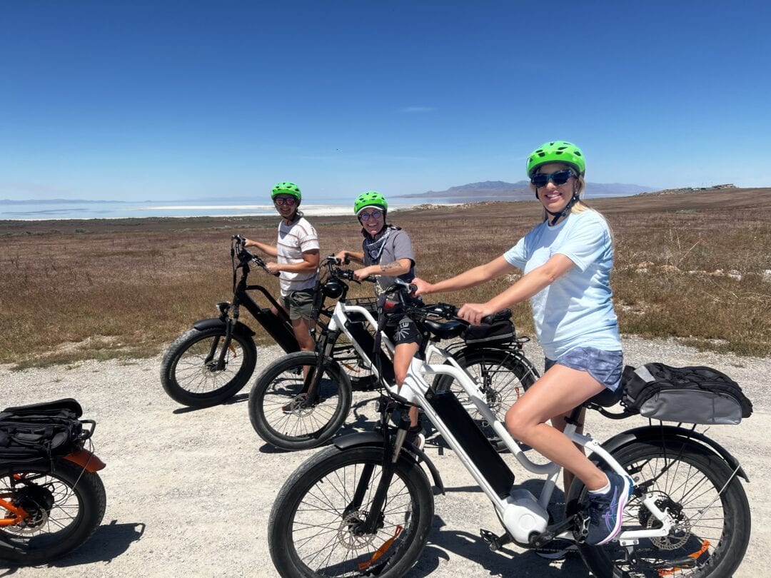 Three women riding electric bikes on a gravel road through a Utah state park