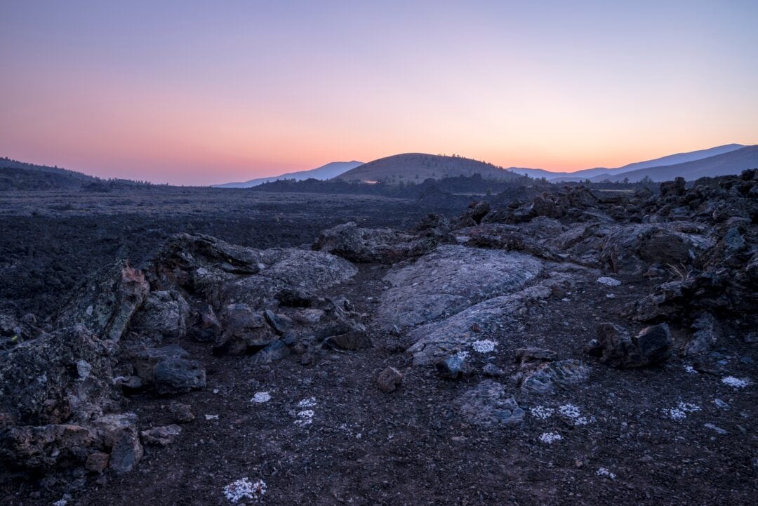 Rock and lava formations near a mountainous region at sunset