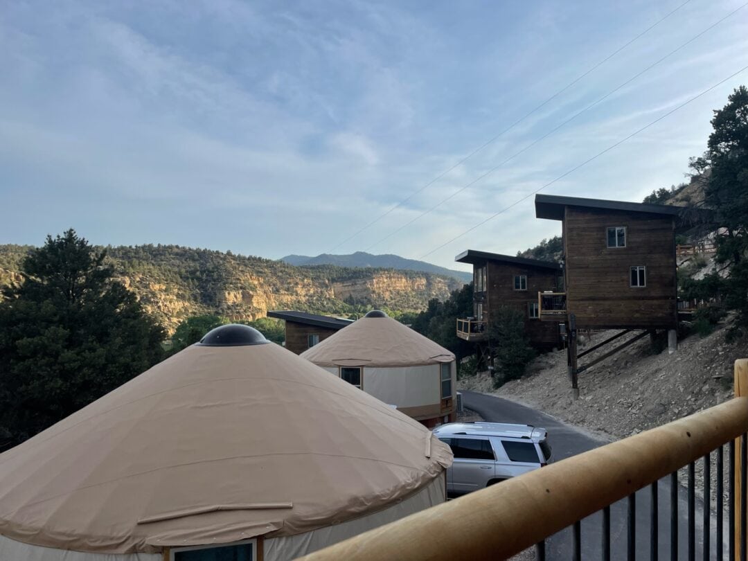 Looking over a balcony to surrounding yurts and treehouses in the mountains