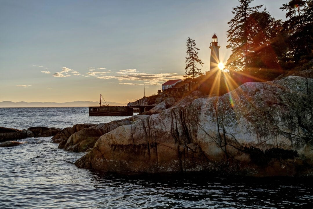 A lighthouse stands atop a rocky shoreline