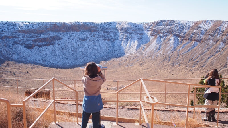 Sightseers look out at a crater carved from a meteor