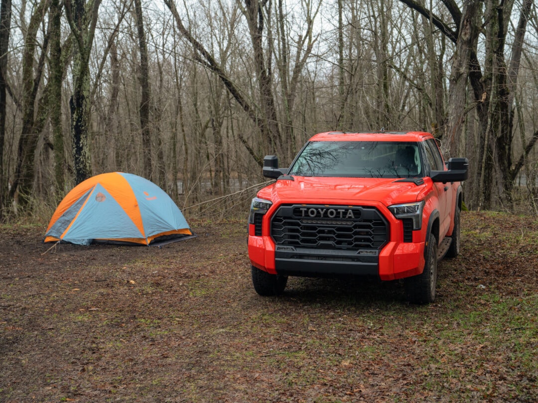 A tent stands next to a Toyota Tundra in a wooded area