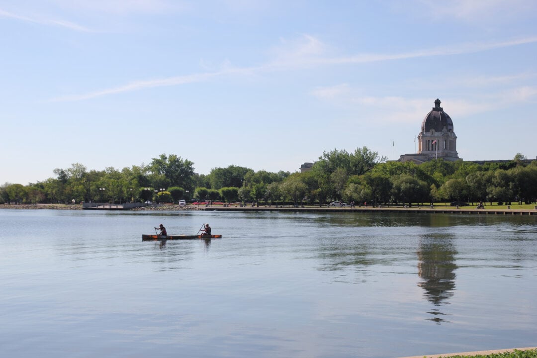 Rowers on Wascana Lake with stately building in background